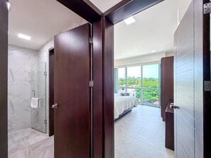 A modern bathroom with a glass shower and a bedroom with a balcony. - Prime Location. 1 BR w/ Ocean View Infinity Pool (Isla Mujeres)