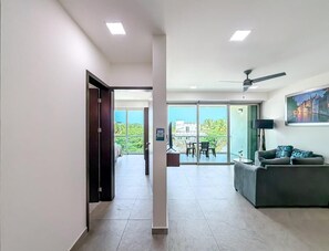 A modern hotel room with a balcony, a dining area, and a living room.