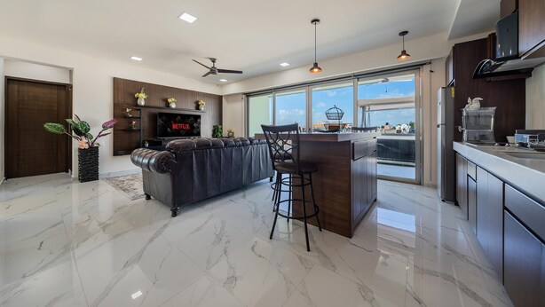 A modern kitchen with a marble floor, a dark leather sofa, a bar area, and a large window offering a view. - 2 BR Condo w/Ocean View Pool. Prime Location (Isla Mujeres)