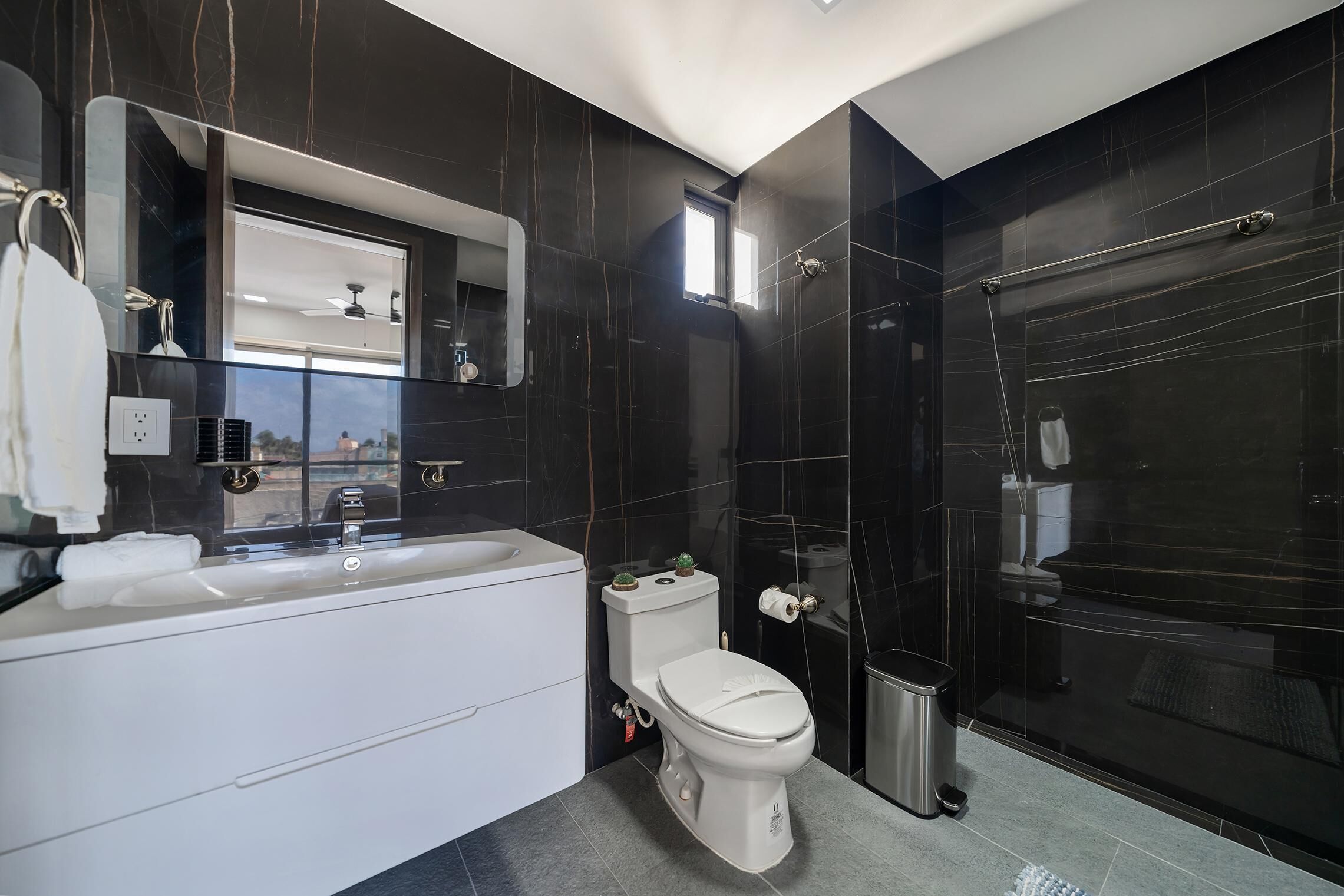 A modern bathroom with a bathtub, toilet, and a glass-enclosed shower area.