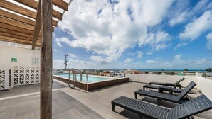 A rooftop pool area with lounge chairs and a pool. - 2 BR Condo w/Ocean View Pool. Prime Location (Isla Mujeres)