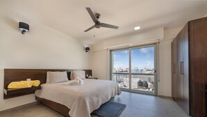 A modern bedroom with a large bed, a ceiling fan, a view through the glass door, and a wardrobe. - 2 BR Condo w/Ocean View Pool. Prime Location (Isla Mujeres)