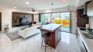 Una cucina moderna con isola centrale, un'area pranzo con divano e un televisore nel soggiorno.