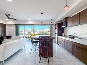 A modern kitchen with a dining area, large windows, and a view of the city.