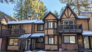 A two-story lodge with a balcony and a covered porch, surrounded by snow and pine trees. - Kuma Lodge, 1 Night Free! (Big Bear Lake)