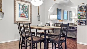 A dining area with a wooden table and chairs, a chandelier, framed artwork, and a wall-mounted sign. - Kuma Lodge, 1 Night Free! (Big Bear Lake)