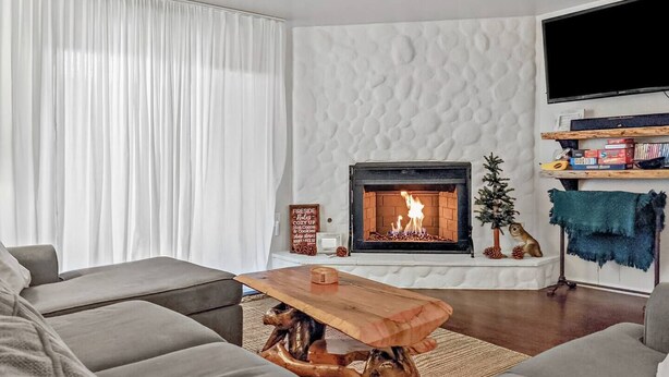 A modern living room with a fireplace, grey sofas, a wooden coffee table, and a TV on the wall. - Kuma Lodge, 1 Night Free! (Big Bear Lake)