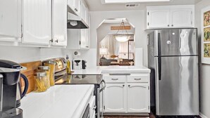 A modern kitchen with white cabinetry, a stainless steel refrigerator, and a skylight above the counter. - Kuma Lodge, 1 Night Free! (Big Bear Lake)