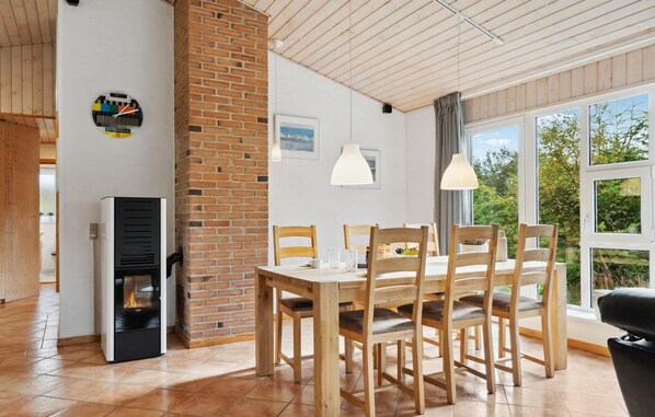 Een eetgedeelte met een metselwerk open haard, een houten tafel en stoelen.