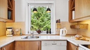 A modern kitchen with wooden cabinets, a stainless steel sink, a Bosch dishwasher, and a window with a view of greenery. - Lovely home in Fjerritslev with WiFi (Fjerritslev)
