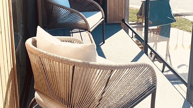 A balcony with wicker chairs and a table, overlooking a vineyard. - Wine, Lake, Repeat I City Edge Retreat Naramata Wine Gateway (Penticton)