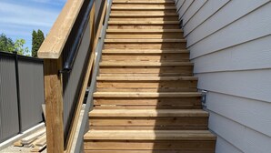 A wooden staircase with a metal handrail, leading up to a building with white siding. - Wine, Lake, Repeat I City Edge Retreat Naramata Wine Gateway (Penticton)