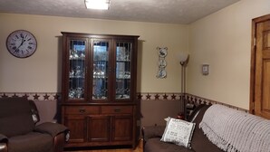 Una sala de estar con un aparador de madera, un reloj, una lámpara y un sofá.
