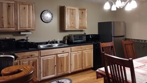 Una cocina con armarios de madera, un refrigerador negro, un microondas y un lavamanos.