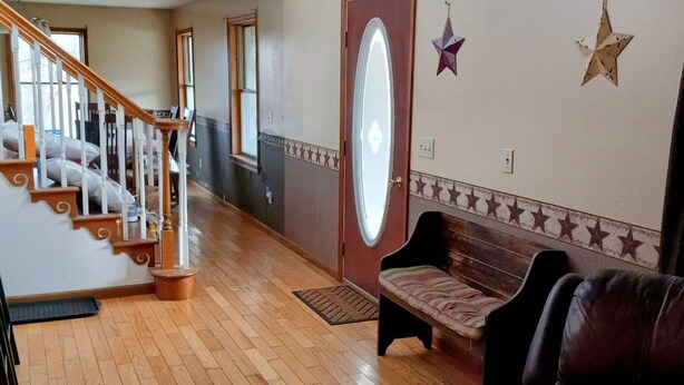 Un vestíbulo amplio con una escalera de madera, un banco y una pared decorada con motivos de estrellas.