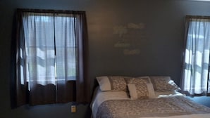 Un dormitorio con cama, cortinas y ventilador de techo.