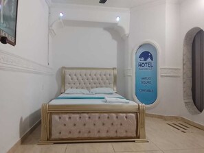 Un dormitorio con una cama grande, un televisor montado en la pared y un cartel que muestra el nombre del hotel y sus servicios.