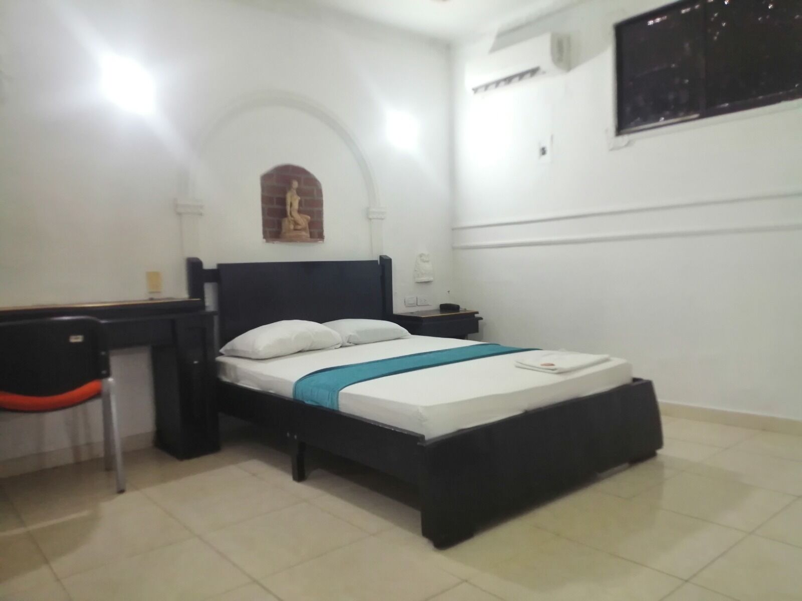 A bedroom with a bed, a desk, and a chair.