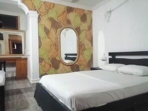 Een slaapkamer met een bed, een bureau en een spiegel.