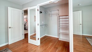 A walk-in closet with open doors, shelves, and a hanging rod.