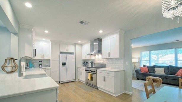 A modern kitchen with white cabinetry, a central island, and a dining area with a table and chairs.