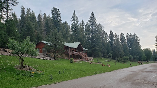 Un chalet avec une façade en bois, un porche et des fondations en pierre.