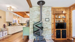 A modern kitchen with wooden cabinets, a stone accent wall, and a built-in wood stove.
