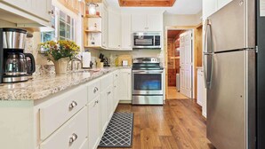 A kitchen with white cabinets, stainless steel appliances, a coffee maker, and a wooden ceiling.