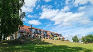 Een meerlaags woongebouw met een schuin dak, bakstenen gevel en meerdere ramen.