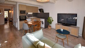 A modern living room with a sofa, a TV, and a dining area with chairs and a table. - Lovely apartment in Rustrel (Rustrel)
