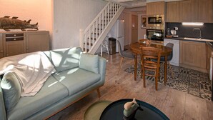 A cozy living room with a light blue sofa, a dining table with chairs, a kitchen area with wooden cabinets and modern appliances, and a staircase leading to another level. - Lovely apartment in Rustrel (Rustrel)