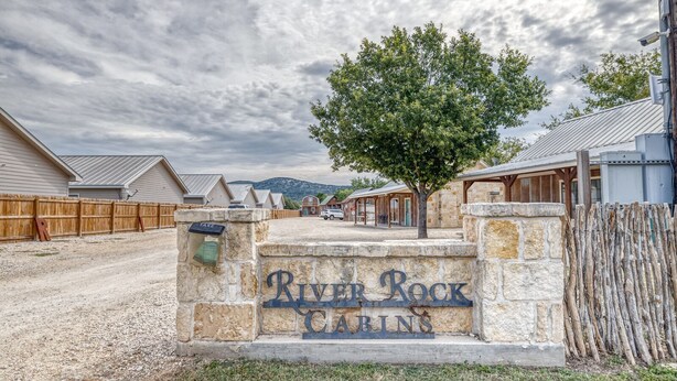 A gravel driveway leading to a stone sign with "River Rock Cabins" written on it.
