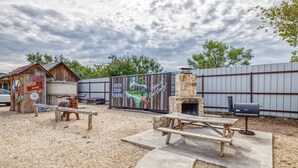 A rustic outdoor area with a wooden cabin labeled 'Dodge', a mural welcoming visitors to 'River Rock Cabins', and a stone fireplace with a grill.