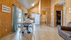 A wooden interior with a dining table, chairs, a sofa, and a kitchen area.