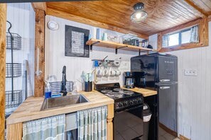 A compact kitchen with a gas stove, a coffee maker, and a refrigerator.