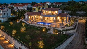 A modern villa with a swimming pool, multiple outdoor seating areas, and a well-maintained garden. - Beach front home in Malinska (Malinska)