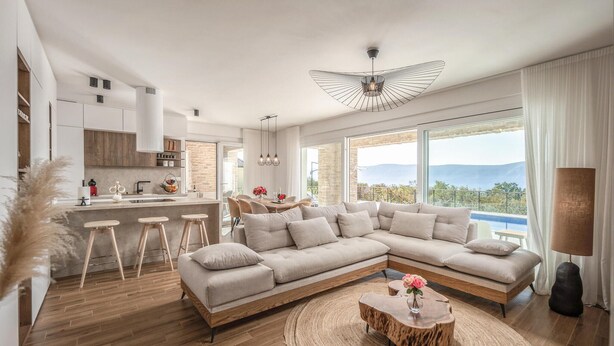 A modern living room with a large L-shaped sofa, a wooden coffee table, and a view of the outdoors. - Beach front home in Malinska (Malinska)