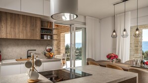 A modern kitchen with a central island, wooden cabinets, and a view to the outdoors. - Beach front home in Malinska (Malinska)