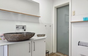 A bathroom with a large stone basin, a small bowl, a mirror, and a toilet.