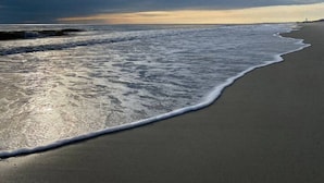 Een strand met een breed zandstrand en rustige golven.