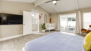 A spacious bedroom with a large bed, a ceiling fan, a TV mounted on the wall, and a sliding glass door leading to a balcony. - Private Family Heated Pool and Spa, 2 King Beds, Cornhole, Grill, Foosball, Game (Richardson)