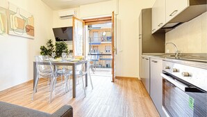 A modern kitchen with stainless steel appliances, a dining area with clear chairs, and a view of a balcony. - 1 bedroom lovely apartment in Recco (Recco)