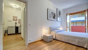 A bedroom with a bed, bedside table, and a nightstand. There is a window with a view of buildings outside. - 1 bedroom lovely apartment in Recco (Recco)
