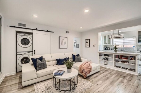A modern living room with a sofa, a coffee table, and a built-in washing machine.