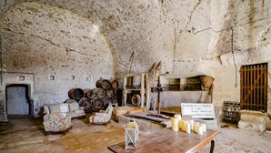 A rustic interior with stone walls, wooden furniture, barrels, and a sign in French. - Manoir de la Salle du Roc - romantic suite 30 M2 Joséphine, Near Chenonceau  (Montrichard Val de Cher)