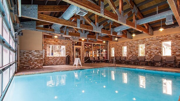 An indoor swimming pool with a stone wall and wooden beams.