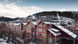 A multi-story building with a red facade and a sloped roof, surrounded by snow-covered terrain and trees.