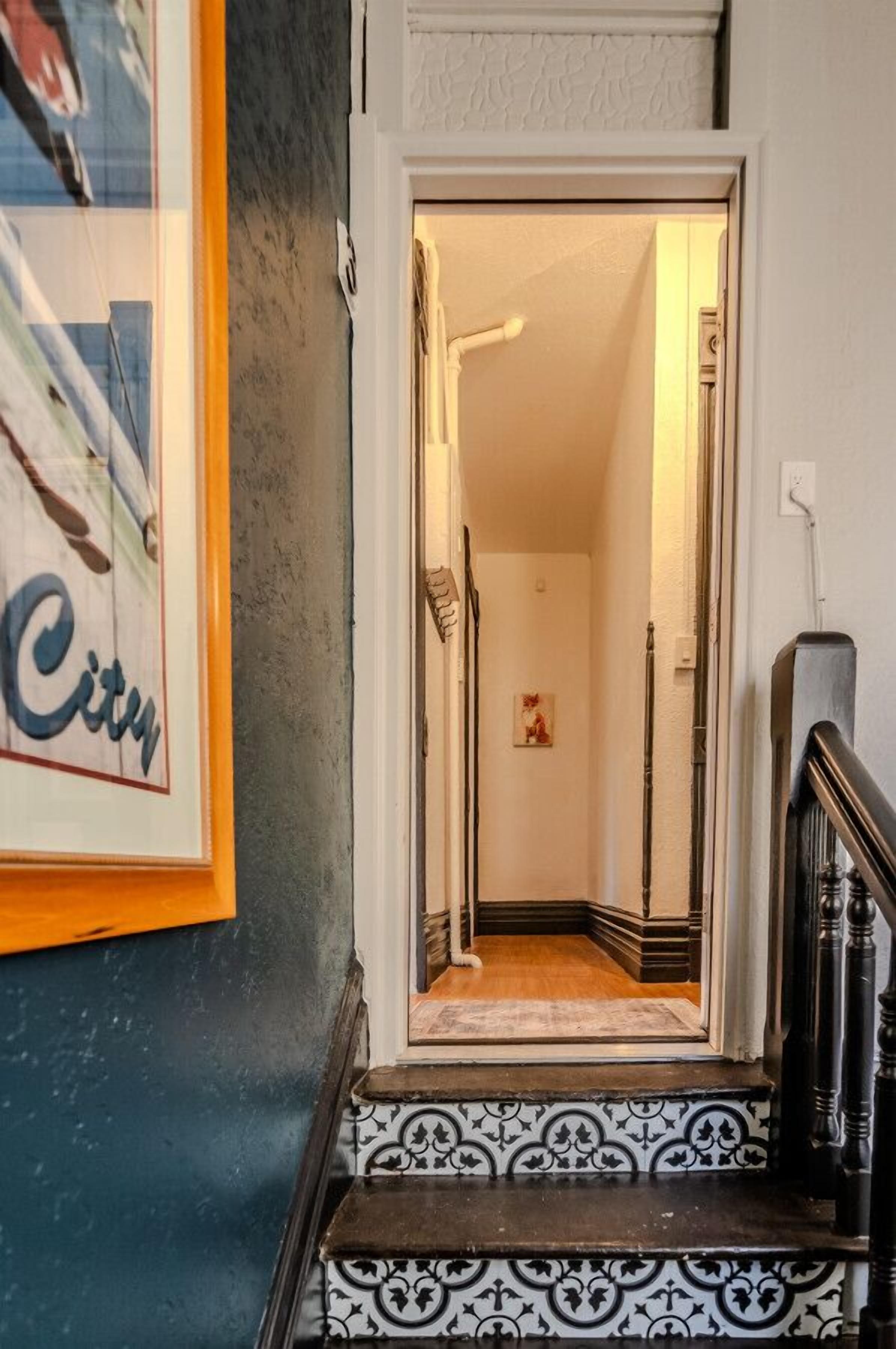 A staircase with black and white patterned steps leading to a hallway with a door at the top.
