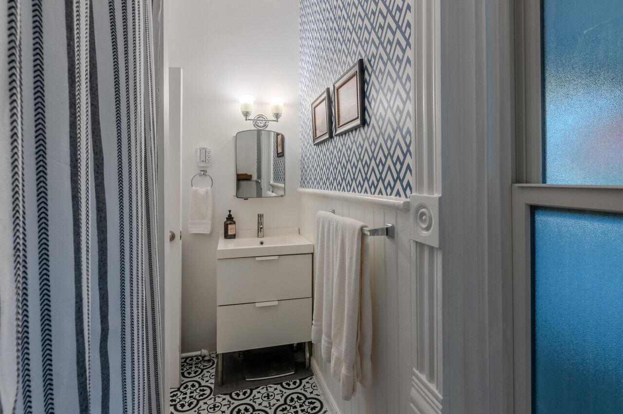 A bathroom with a white vanity, a mirror, and a patterned wall.
