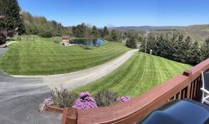 Une pelouse bien entretenue, agrémentée d’une terrasse en bois, d’un petit étang et offrant une vue dégagée sur le paysage environnant.